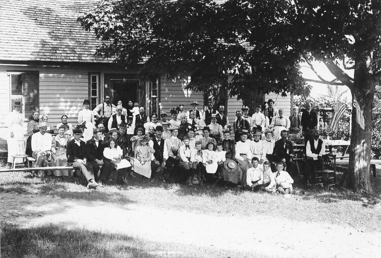 A black and white photo showing a large family in front of the Robinson home