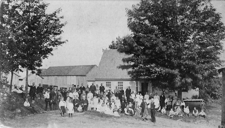 A black and white photo showing a large family in front of the Robinson home